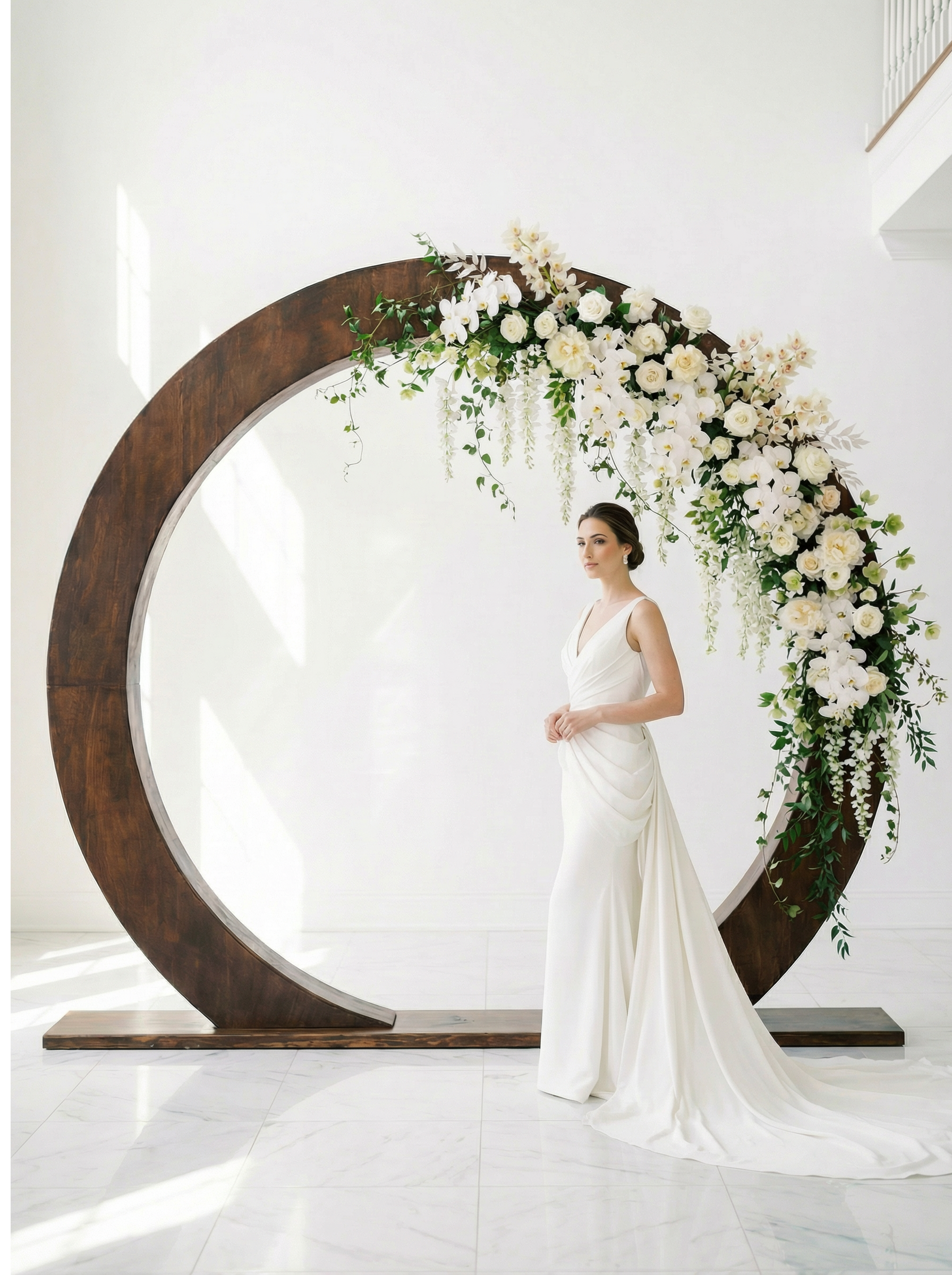 Bride framed by the dark walnut ceremony arch with cascading white florals